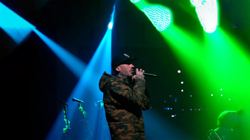 Pablo Nicasso cantando en directo sobre un escenario con luces verdes y azules